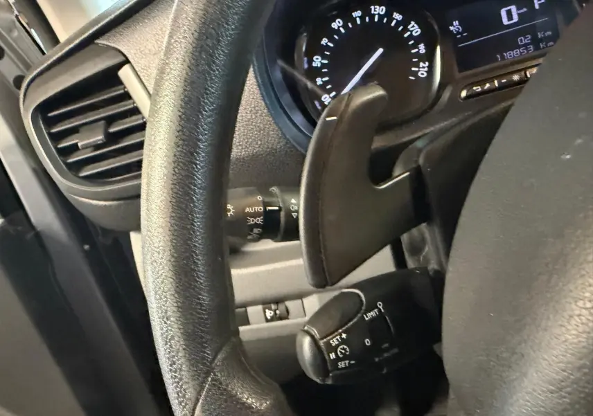 Gros plan sur le volant et le tableau de bord du Citroën Jumpy gris, montrant la commande de régulateur de vitesse et le compteur.