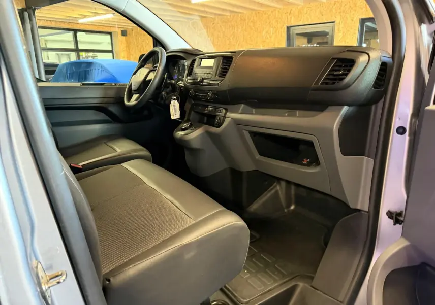Vue intérieure côté conducteur du Citroën Jumpy gris 2022, montrant le tableau de bord et la banquette avant.