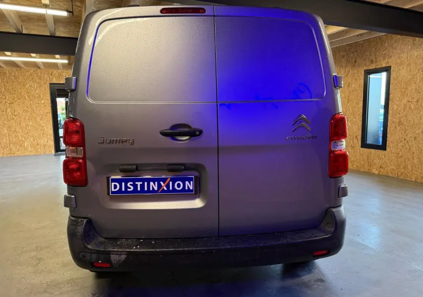 Vue arrière d'un Citroën Jumpy gris métallisé 2022 avec portes battantes et plaque Distinxion en intérieur.