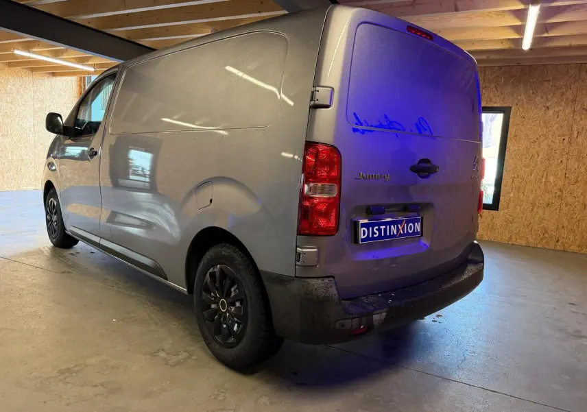 Vue 3/4 arrière droite d'un Citroën Jumpy gris métallisé 2022 avec portes battantes et jantes noires en intérieur.