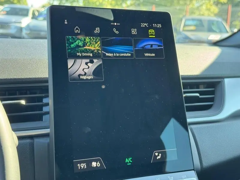 Écran tactile central du tableau de bord du Renault Captur blanc nacré 2025, affichant les menus d’aide à la conduite.