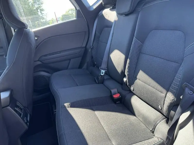 Vue intérieure des sièges arrière noirs du Renault Captur 2025, avec ceinture de sécurité et lumière naturelle.
