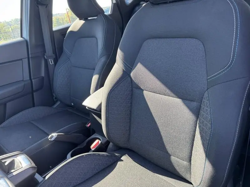 Gros plan sur les sièges avant noirs du Renault Captur 2025, avec coutures apparentes et tissu texturé, vue côté droit.