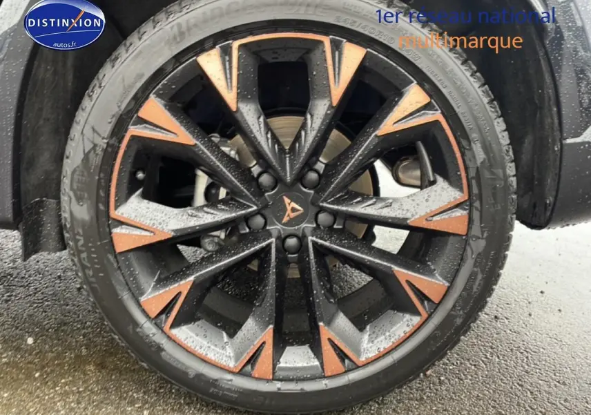 Gros plan sur la jante noire et cuivre du CUPRA Formentor gris Graphene, avec pneus Bridgestone mouillés.