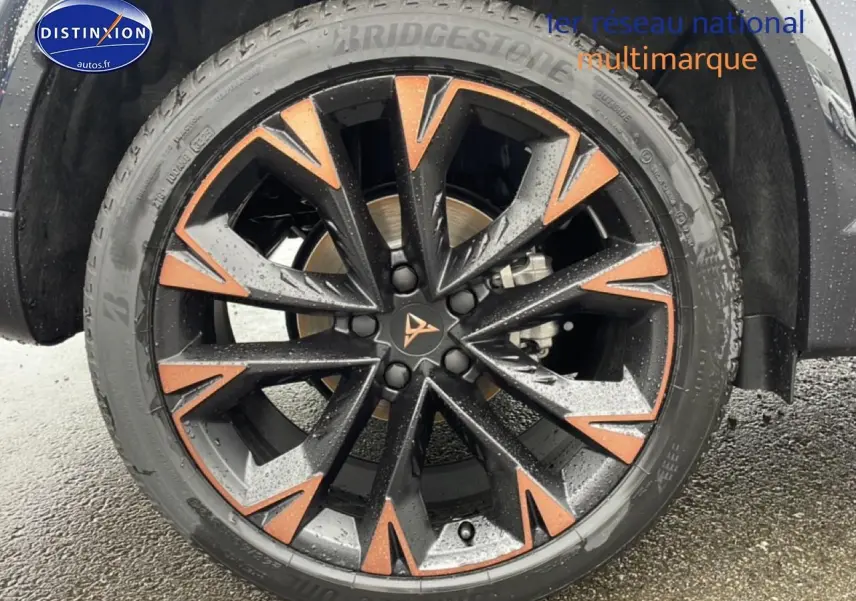 Gros plan sur la jante noire et cuivre du CUPRA Formentor 2.0 TDI 150 DSG7 gris graphene, avec pneu Bridgestone humide.