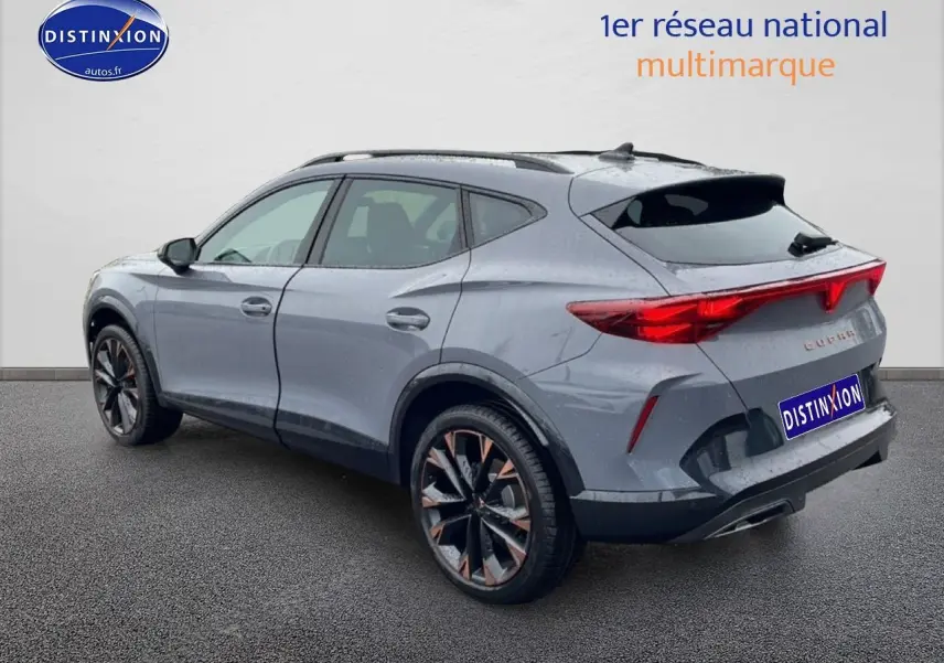 Vue 3/4 arrière droite d’un CUPRA Formentor gris graphene avec jantes noires et bronze, feux arrière LED allumés.