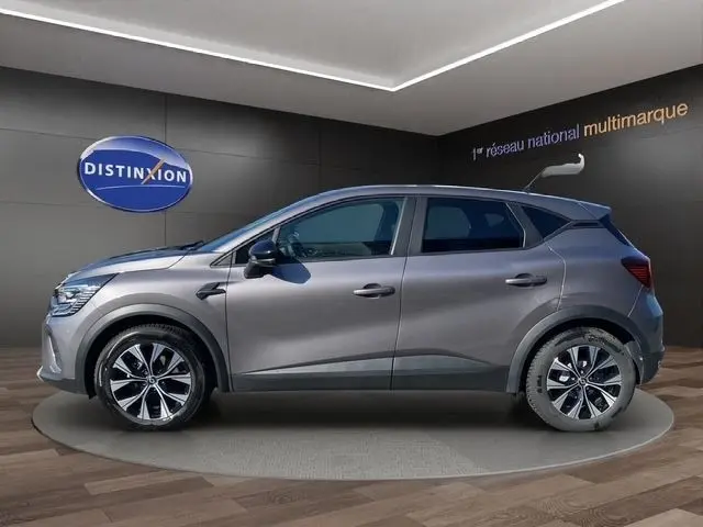 Vue de profil côté gauche d’un Renault Captur gris clair 2023 avec jantes alliage et rétroviseurs noirs.