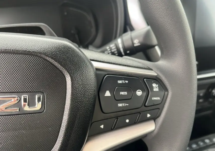 Gros plan sur le volant multifonctions noir de l'Isuzu D-MAX 2.2 TD 164 Space Evolution avec commandes de régulateur.