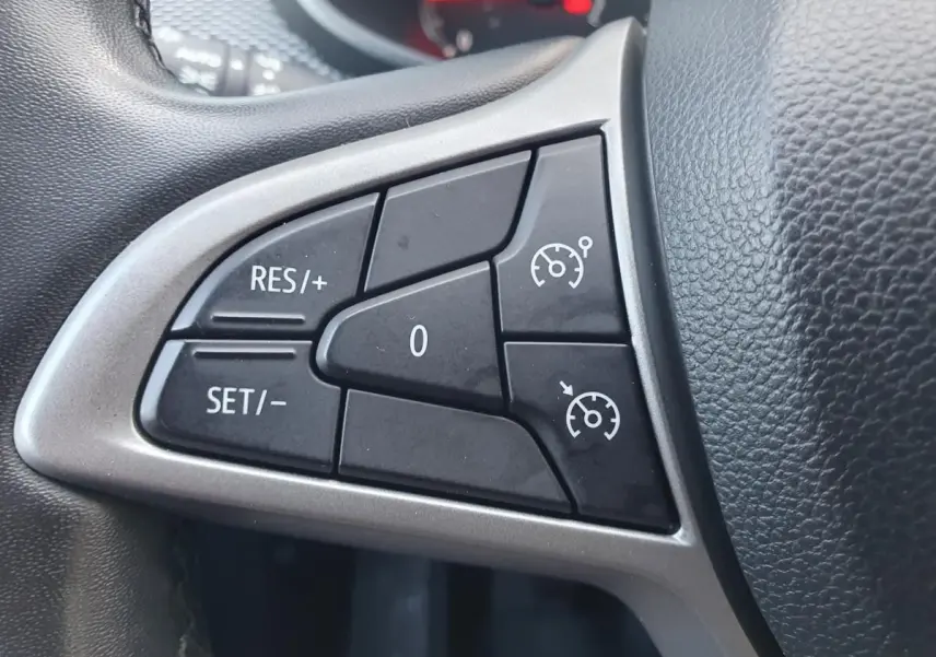 Gros plan sur les commandes du régulateur de vitesse au volant d’une Dacia Sandero gris urbain 2024.