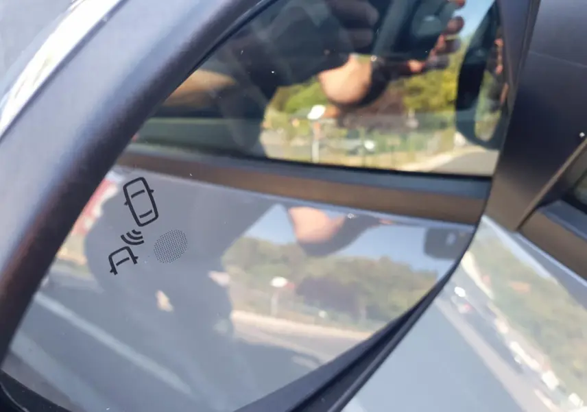 Rétroviseur droit de la Dacia Sandero gris urbain 2024 avec alerte d'angle mort visible sur le miroir.