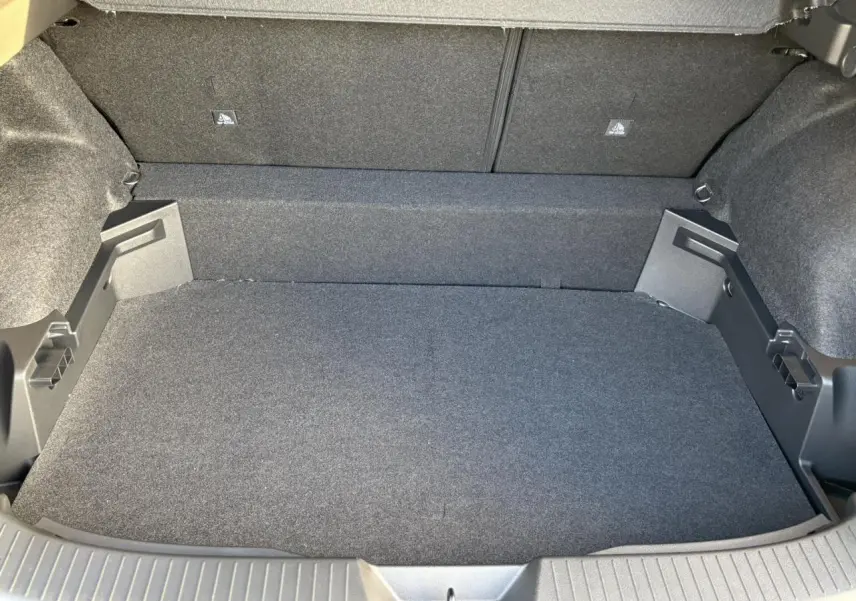 Coffre ouvert du Nissan Qashqai III noir Kuro, vue intérieure montrant le tapis et les parois en tissu gris.