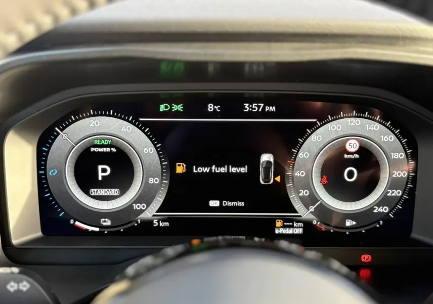 Vue rapprochée du combiné numérique du Nissan Qashqai III e-Power, affichant un avertissement de faible carburant.