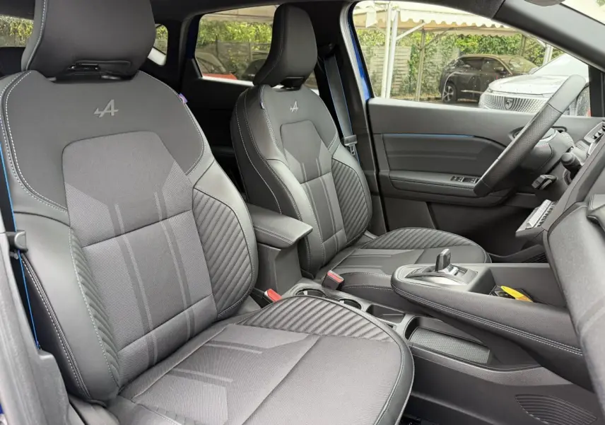 Vue intérieure avant du Renault Captur Esprit Alpine bleu, sièges noirs avec logo Alpine brodé sur appuie-têtes.