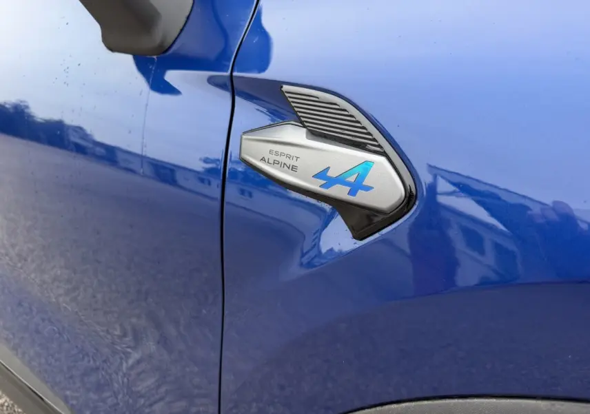 Détail du logo Esprit Alpine bleu sur l'aile avant gauche d'un Renault Captur bleu 2026.