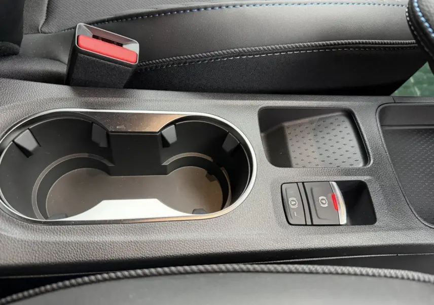 Gros plan sur la console centrale noire du Renault Captur 2026 avec porte-gobelets et commandes frein à main électrique.
