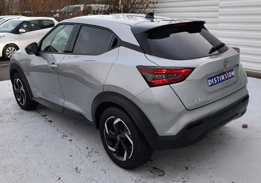 Nissan Juke 2024 gris perle métal vu en 3/4 arrière droit, avec feux arrière LED et toit noir contrasté.