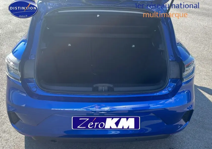 Vue arrière d'une Renault Clio V bleu iron avec coffre ouvert montrant l'espace de chargement vide.