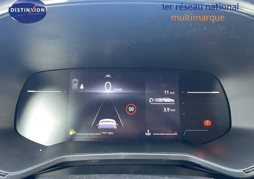 Tableau de bord numérique de la Renault Clio 1.5 DCI 100ch Evolution affichant la vitesse et alertes, vue frontale.