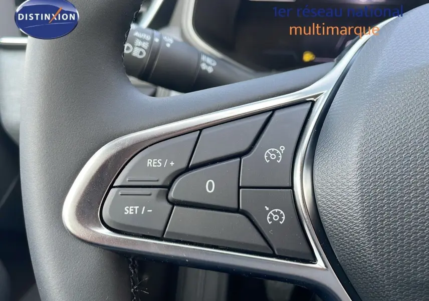 Gros plan sur les commandes de régulateur de vitesse au volant d'une Renault Clio 1.5 DCI noir étoile métal, intérieur moderne.