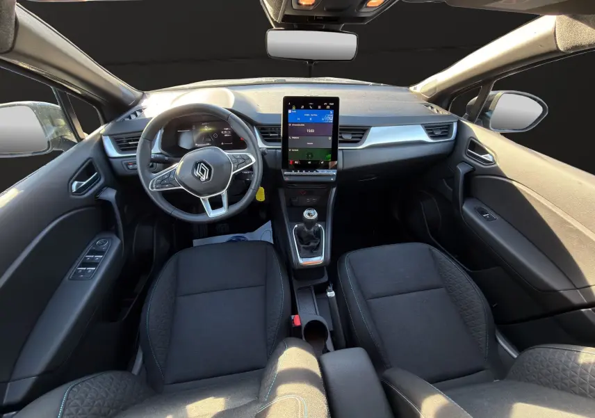 Vue intérieure avant du Renault Captur 2024, tableau de bord avec écran tactile vertical et volant multifonctions.