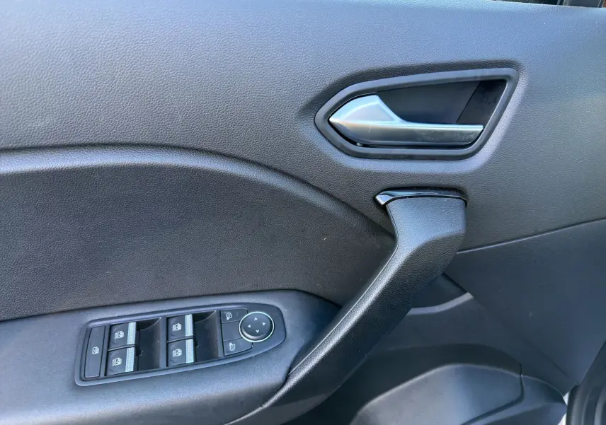 Gros plan sur la poignée intérieure et les commandes de vitres côté conducteur du Renault Captur 2024, finition noire.