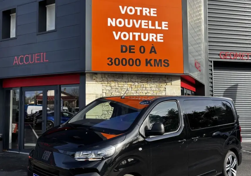 Fiat Scudo Fourgon noir en 3/4 avant droit, stationné devant un bâtiment avec enseigne orange Distinxion.