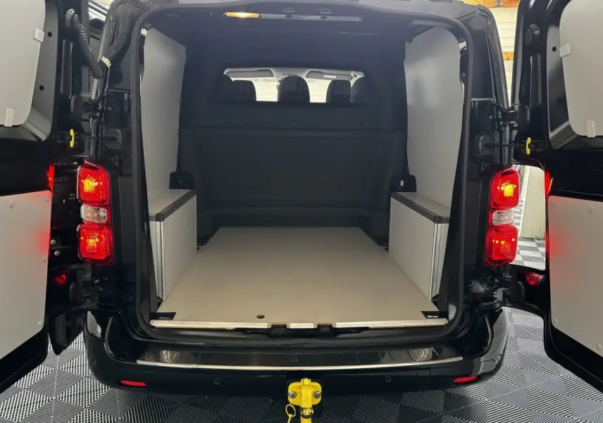 Vue arrière du FIAT Scudo Fourgon noir 2025 avec portes ouvertes et espace de chargement aménagé, attelage visible.