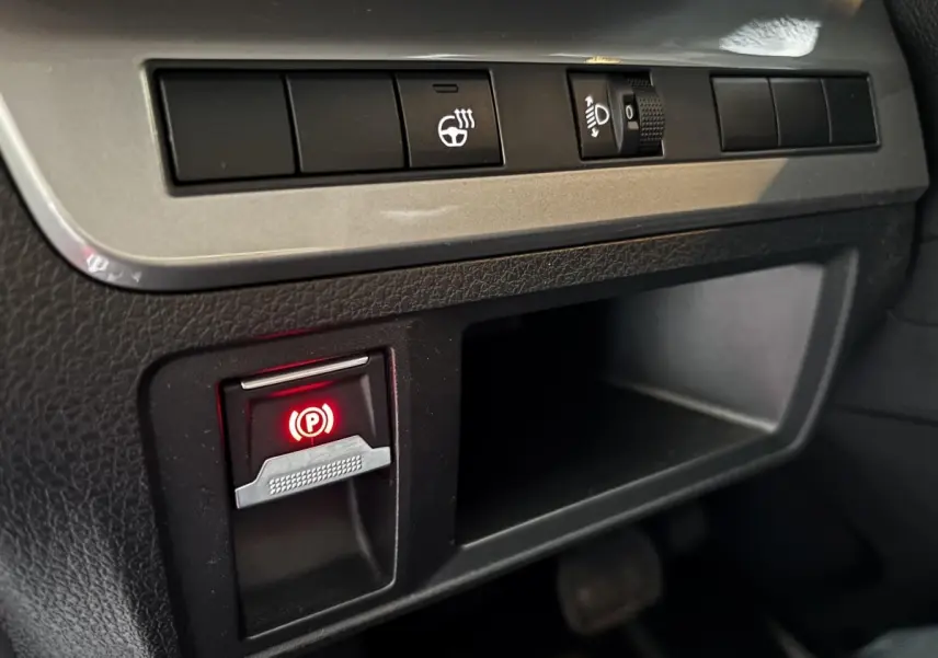 Gros plan sur les commandes du frein à main électrique et réglage des phares dans l'habitacle du FIAT Scudo Fourgon noir 2025.