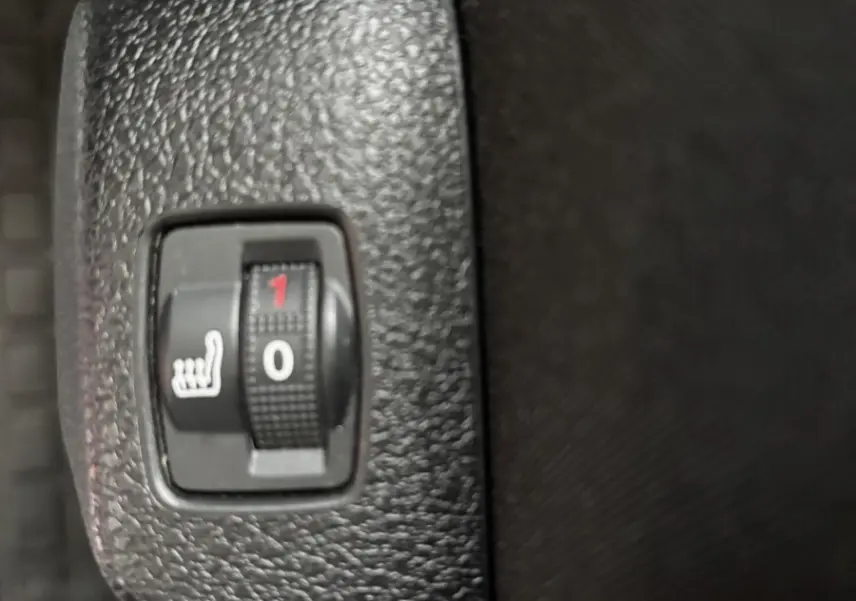 Gros plan sur le bouton de réglage du siège chauffant noir dans l'habitacle du Fiat Scudo Fourgon 2025.