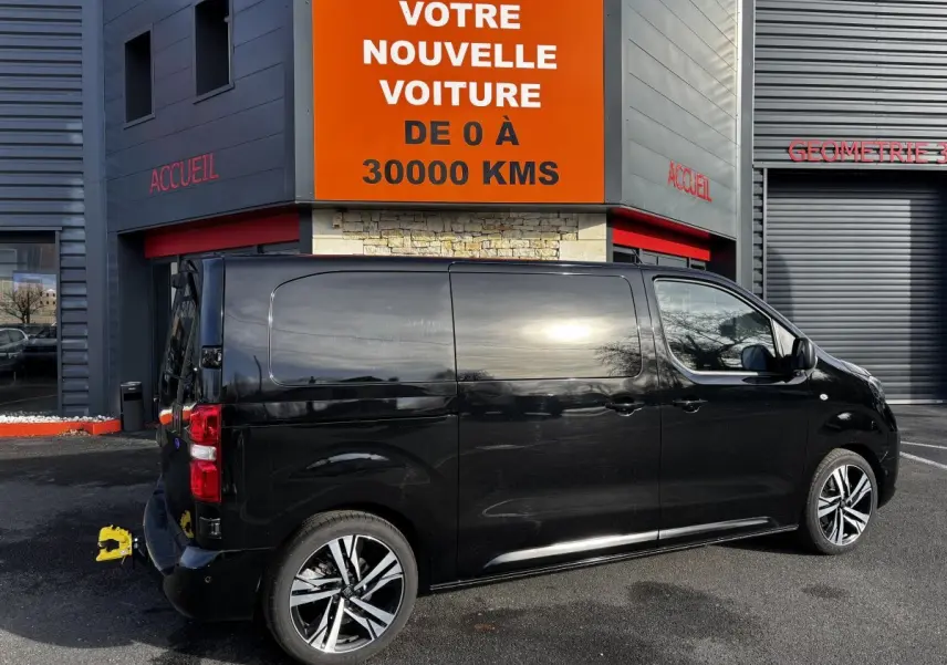 FIAT Scudo Fourgon noir vu de profil côté droit, stationné devant un bâtiment avec enseigne orange.