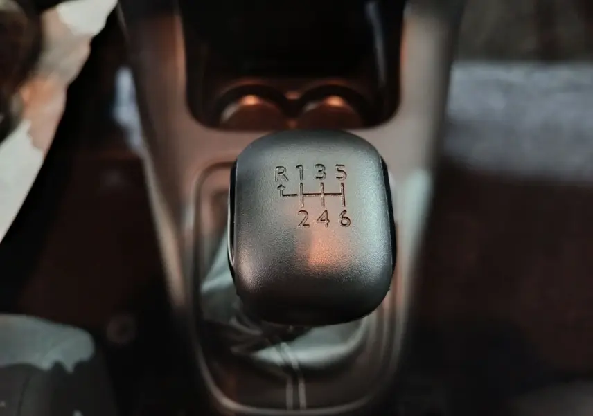 Gros plan sur le levier de vitesses manuel noir de la Citroën C3 BlueHDi 100, intérieur sombre.