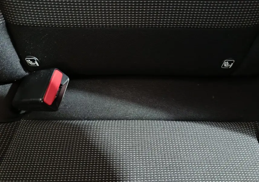 Gros plan sur la banquette arrière grise à motifs avec boucle de ceinture et indicateurs Isofix visibles.