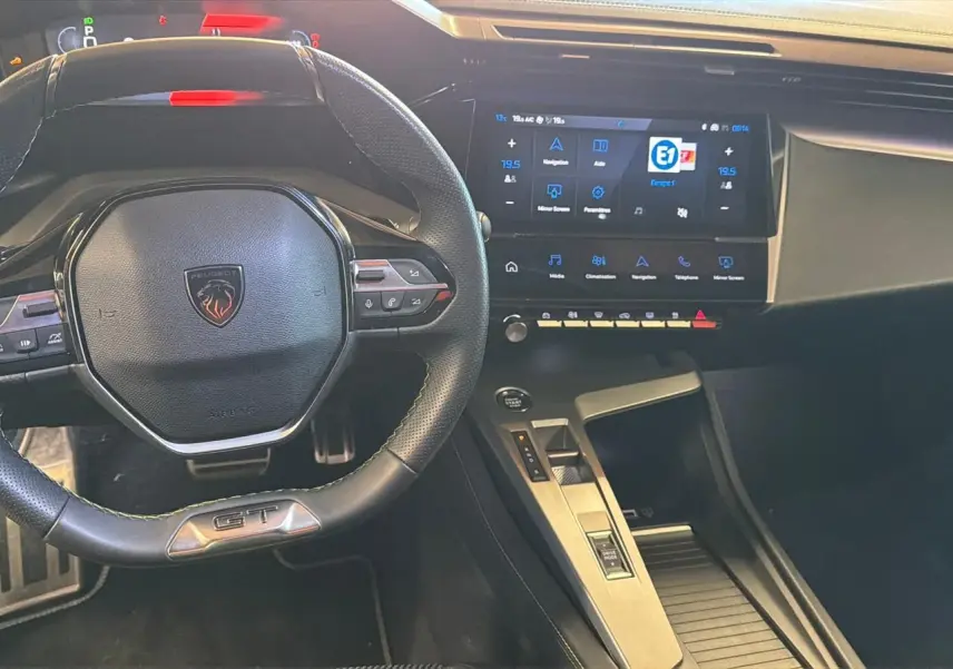 Vue intérieure centrée sur le volant GT noir et l'écran tactile 10 pouces du tableau de bord du Peugeot 408 gris.
