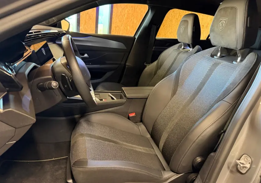Vue intérieure côté conducteur de la Peugeot 408 gris, sièges tri matières avec logo Peugeot brodé sur appuis-tête.