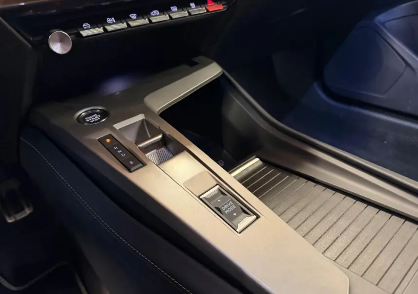 Gros plan sur la console centrale grise de la Peugeot 408 2025 avec bouton Drive Mode et démarrage sans clé.