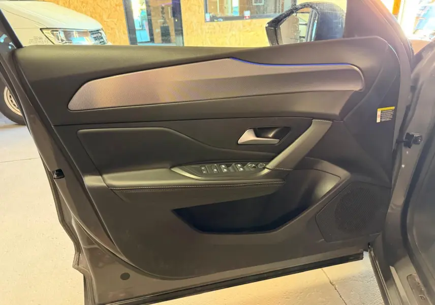 Vue intérieure de la porte avant gauche grise du Peugeot 408 2025 avec garniture noire et surpiqûres claires.