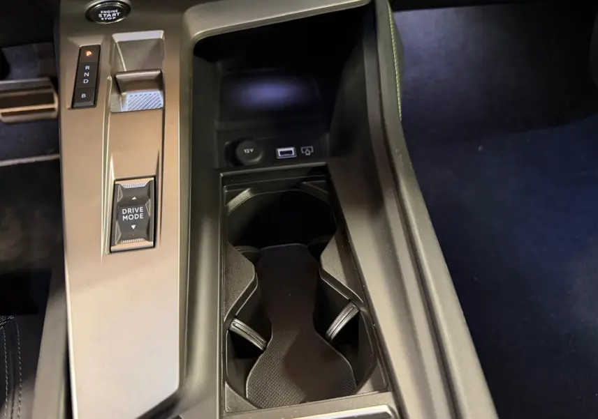 Vue rapprochée de la console centrale noire avec sélecteur de modes et porte-gobelets du Peugeot 408 gris 2025 hybride rechargeable.