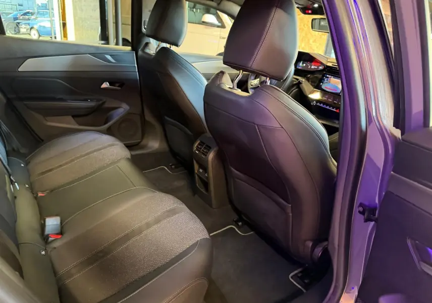 Vue intérieure arrière droite de la Peugeot 408 gris, montrant les sièges bi-matière et la console centrale avec aérateurs.