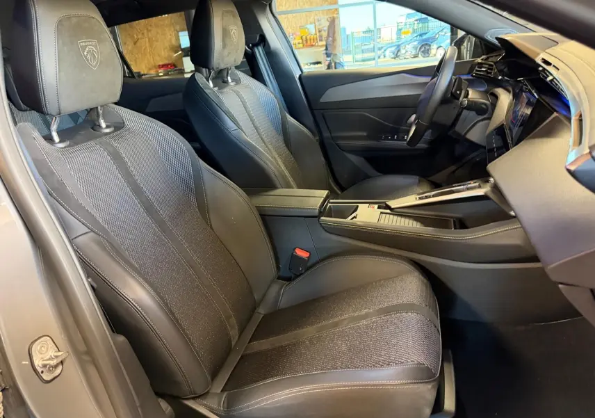 Vue intérieure côté conducteur de la Peugeot 408 gris, sièges tri matières avec logo Peugeot embossé sur appuie-tête.