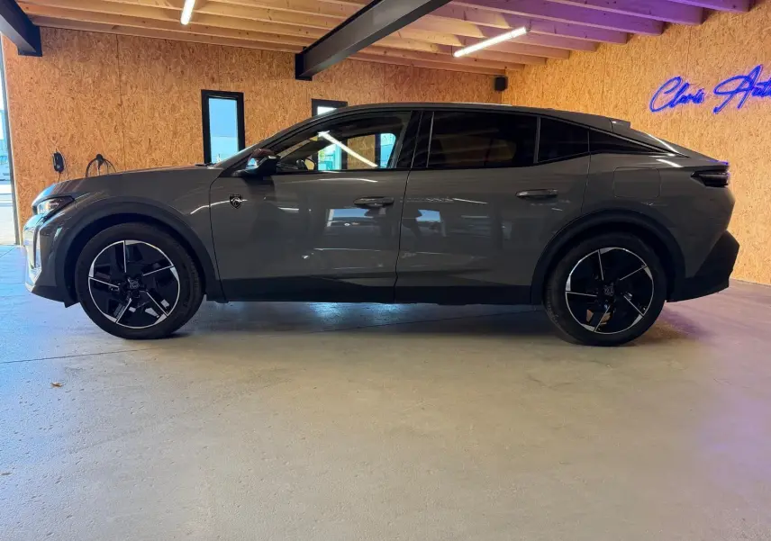 Vue de profil côté gauche d'une Peugeot 408 gris métallisé avec jantes 19'' diamantées et vitres surteintées dans un garage.