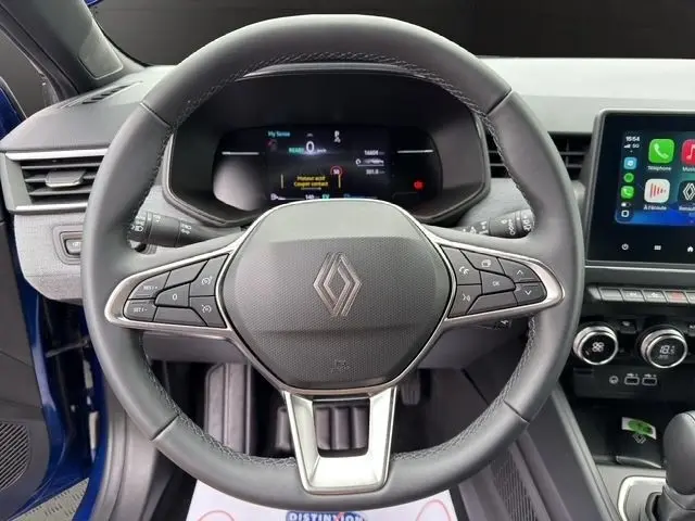 Vue rapprochée du volant cuir synthétique multifonctions de la Renault Clio Techno E-Tech 2025 avec tableau de bord numérique et écran tactile.