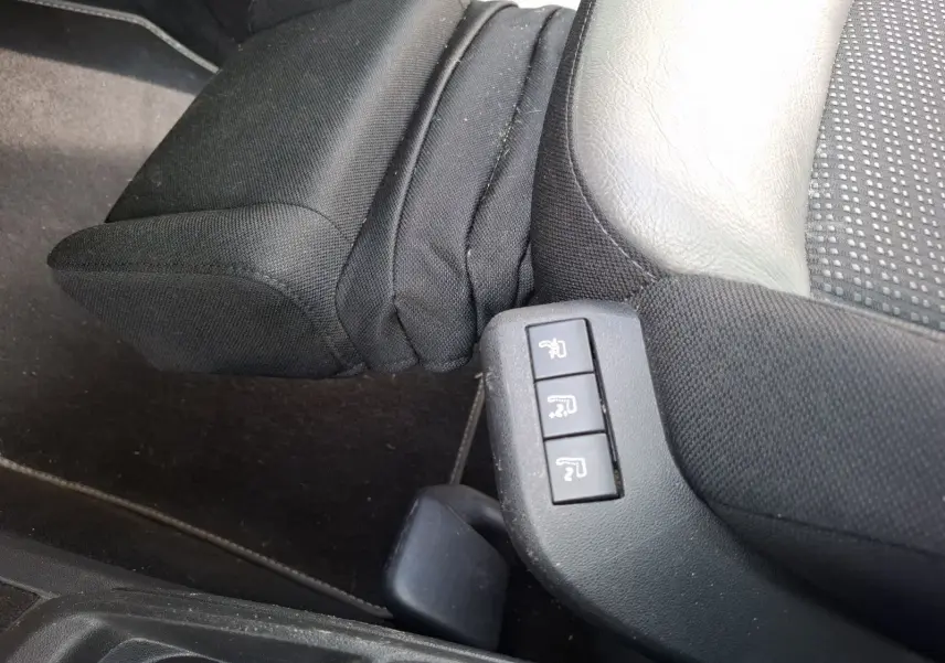Boutons de réglage des sièges massants sur le côté droit d’un siège avant en cuir et tissu noir du Citroën C4 Picasso gris clair.