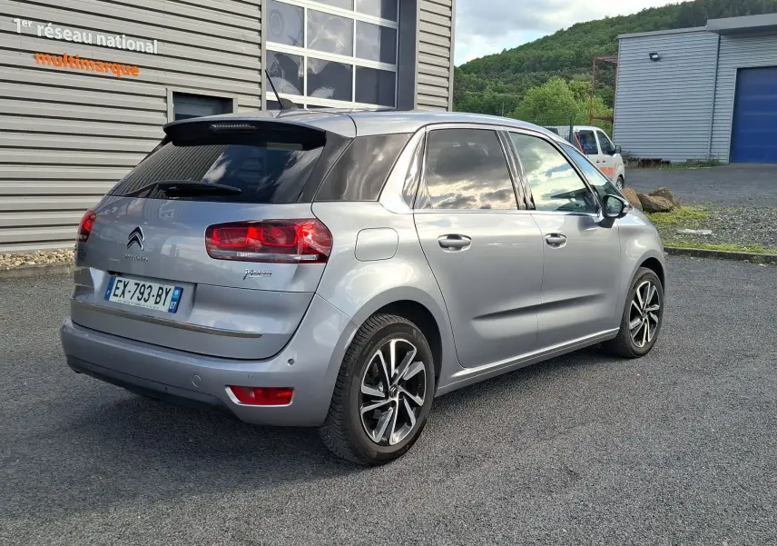 Vue 3/4 arrière droite d'une Citroën C4 Picasso gris clair avec jantes alliage 17 pouces et toit panoramique.