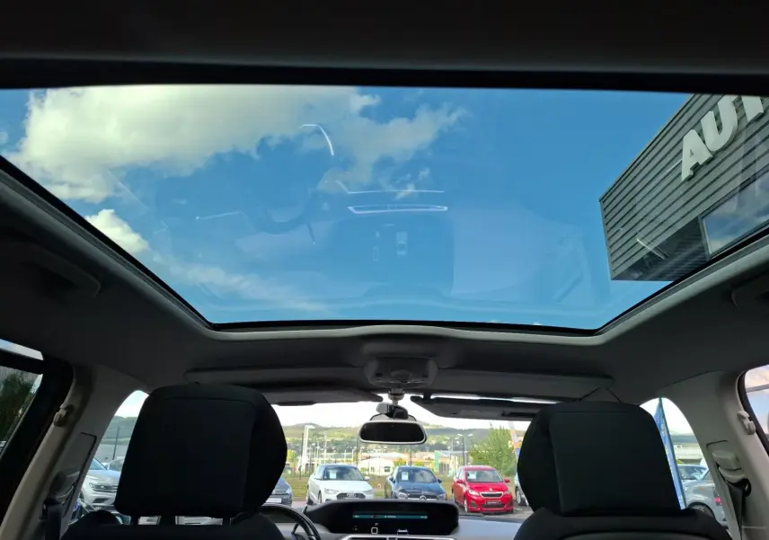 Vue intérieure du toit panoramique du Citroën C4 Picasso gris clair, avec sièges avant et tableau de bord visibles.