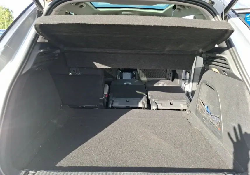 Coffre ouvert vu de l’arrière d’une Citroën C4 Picasso gris clair avec banquette arrière partiellement rabattue.