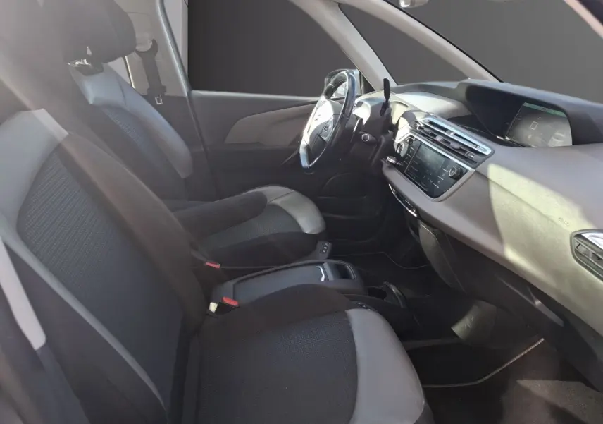 Vue intérieure côté conducteur de la Citroën C4 Picasso gris clair, avec sellerie cuir et tissu et tableau de bord moderne.