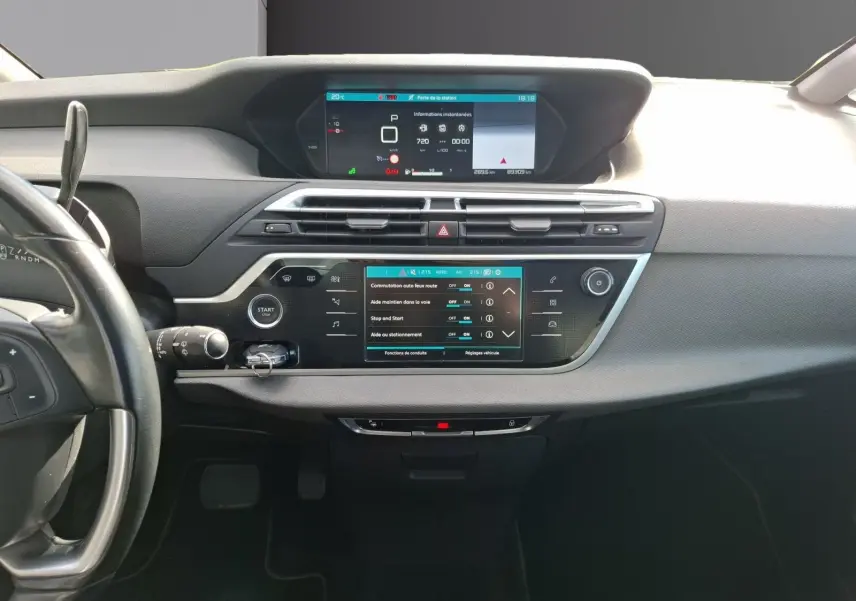 Vue frontale de l’intérieur du Citroën C4 Picasso gris clair, avec tableau de bord numérique et écran tactile central.
