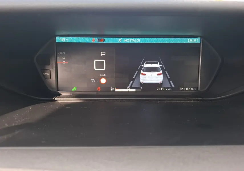 Affichage numérique du tableau de bord de la Citroën C4 Picasso montrant la voiture blanche en vue arrière et les informations de conduite.