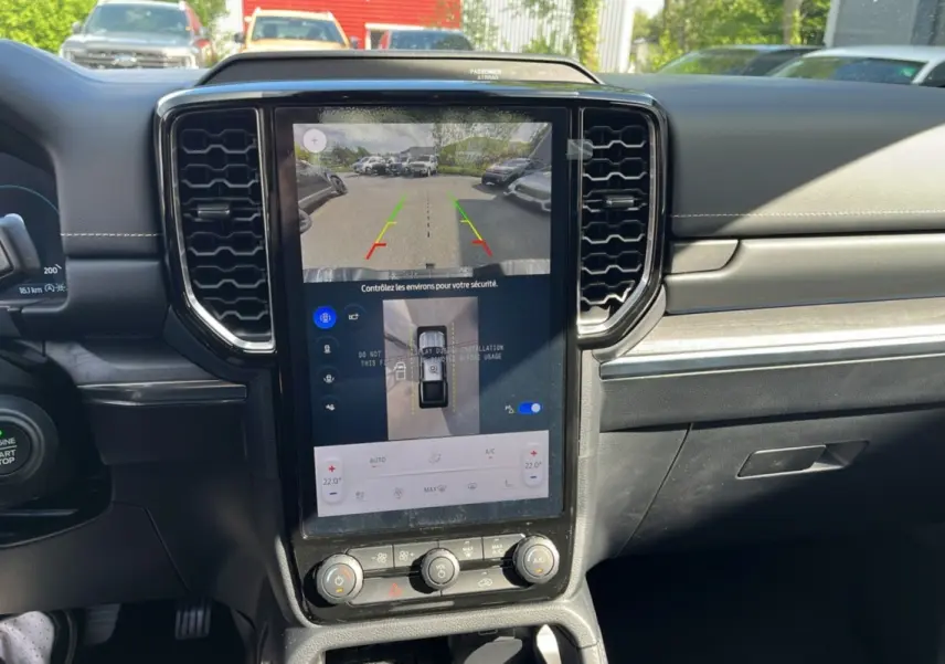 Vue intérieure centrée sur l'écran tactile vertical du tableau de bord du Ford Ranger 2026 avec commandes climatisation et caméra de recul affichée.