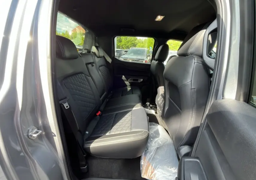 Vue intérieure arrière côté gauche du Ford Ranger gris iconic, montrant les sièges en cuir noir matelassé et le rideau coulissant.